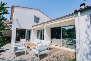 a patio with white chairs and a wooden table at Villa des Terroirs in La Couarde-sur-Mer