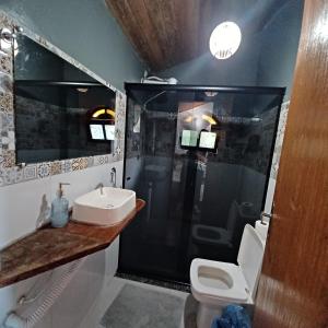 uma casa de banho com um chuveiro, um lavatório e um WC. em Saracura em Praia de Araçatiba