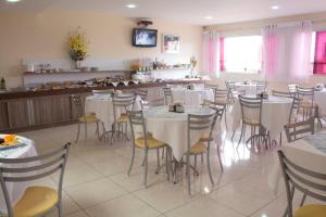 une salle à manger avec des tables et des chaises blanches dans l'établissement Hotel Agua Marinha, à Natal