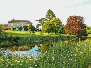 a house in the middle of a field with a pond at West Lexham Manor in Kings Lynn