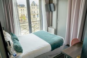 a bedroom with a bed and a large window at Hôtel Central in Poitiers