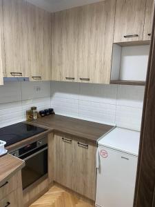 a kitchen with wooden cabinets and a white refrigerator at Centar Apartment in Kumanovo