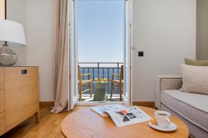 a living room with a coffee table and a balcony at Anaya Suites in Ermoupoli