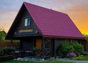 eine Holzhütte mit einem lila Dach und einem Haus in der Unterkunft Trijų žvaigždučių palapinė Vilniuje in Vilnius