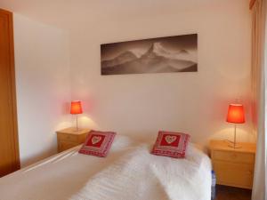 1 dormitorio con 2 almohadas rojas en una cama en Apartment Les Mischabels-2 by Interhome, en Crans-Montana