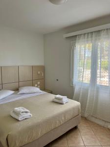 a bedroom with two beds and a window with towels at Naftilos Rosmarinus Apartments in Potokáki