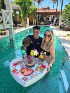 a man and woman with a tray of food in a pool at Ville Sweet Home in Canoa Quebrada