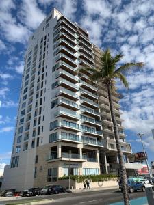 a tall building with a palm tree in front of it at Ocean View Condo in Mazatlán