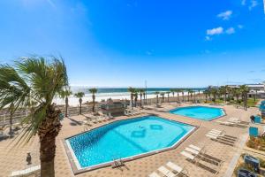 a pool with chairs and a palm tree and the beach at The Summit 1130 in Panama City Beach
