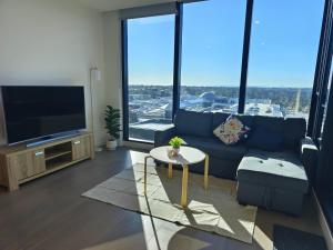 a living room with a blue couch and a tv at Skygarden On The Glen in Glen Waverley