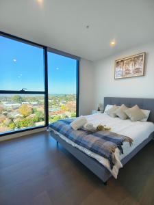a bedroom with a large bed with large windows at Skygarden On The Glen in Glen Waverley