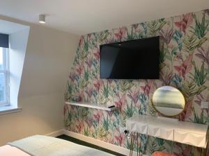 a tv on a wall with a flowery wallpaper at STAG & THISTLE HOTEL AND RESTAURANT in Fraserburgh