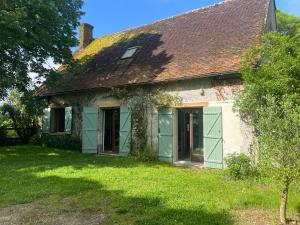an old house with green doors and a grass yard at Charmante maison de campagne in Le Charme