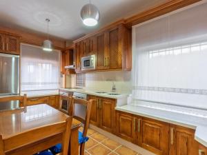 eine Küche mit Holzschränken, einem Tisch und einer Spüle in der Unterkunft Holiday Home Villa San Vicente by Interhome in Baena