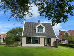 a house with a roof and a grass yard at Recreatiepark Wiringherlant in Hippolytushoef