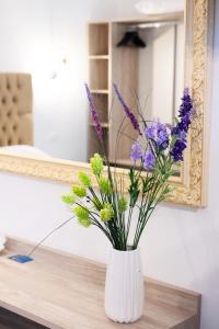 un jarrón con flores púrpuras en una mesa frente a un espejo en Serenity Luxe Suites en Parga