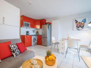 sala de estar con sofá y cocina con armarios rojos. en Studio Ulysse Plage-5 by Interhome, en La Grande-Motte