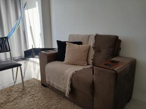 APARTAMENTO EM GARANHUNS PERTO De TUDO في غارانيونز: أريكة بنية الجلوس في غرفة المعيشة مع طاولة