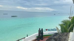 tres personas de pie en una pared mirando al océano en Blue Tides Hotel en Nungwi