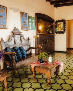 Habitación con banco de madera y mesa. en Hotel Ciudad Vieja en Guatemala