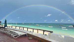 un arco iris sobre una playa con un banco y un muelle en Blue Tides Hotel en Nungwi
