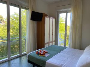a bedroom with a bed with a television and large windows at Pinetina Mare Baby Family Hotel in Cervia