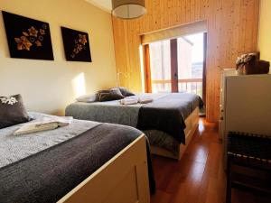 a bedroom with two beds and a window with a balcony at Casa da Serra - T1 - Penhas da Saúde in Penhas da Saúde