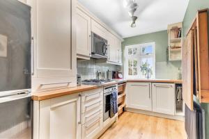 a kitchen with white cabinets and a stove top oven at Charming Reigate Redhill Cottage in Reigate