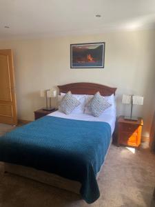 a bedroom with a bed with a blue blanket and two lamps at Park Place Apartments in Killarney