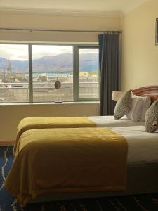 two beds in a hotel room with a large window at Park Place Apartments in Killarney
