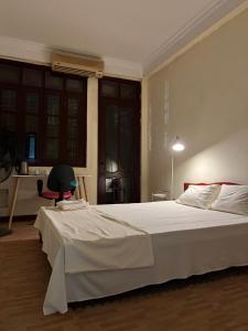 a bedroom with a large white bed and a chair at Tropical land little Hanoi homestay in Hanoi