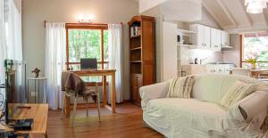 ein Wohnzimmer mit einer weißen Couch und einer Küche in der Unterkunft La Casita del Bosque in San Martín de los Andes