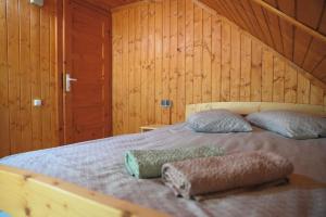 a bed in a wooden room with two pillows on it at Cabana Toth Mic&Mare in Sovata