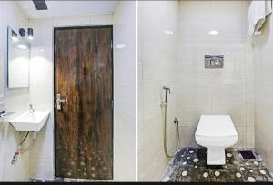 a bathroom with a toilet and a sink and a wooden door at Tavakkal Hotel Near Bandra Kurla Mumbai in Mumbai