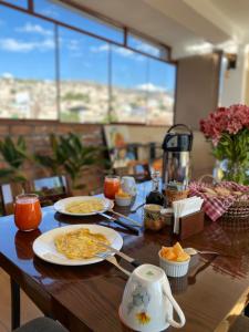 uma mesa de madeira coberta com pratos de comida para o pequeno-almoço em Prince Hospedaje em Ayacucho