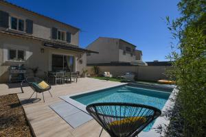 a backyard with a swimming pool and chairs and a house at Entre les Alpilles, la Mer, la Camargue, à huit kilomètres de ARLES ,Villa des jasmins ,piscine,3 chambres ,climatisation, wifi fibre in Raphèle