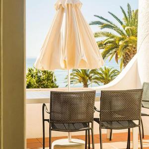 a table with two chairs and a white umbrella at Apartamentos Borda D´Agua in Albufeira