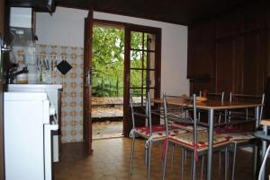 eine Küche mit Tisch und Stühlen und einer Tür in der Unterkunft Maison chaleureuse en Pays-de-Belvès avec terrasse et jardin in Belvès + 6 Fotos