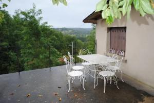 einen Tisch und Stühle auf dem Balkon eines Hauses in der Unterkunft Maison chaleureuse en Pays-de-Belvès avec terrasse et jardin in Belvès