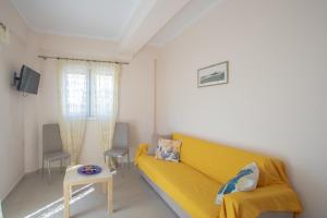 sala de estar con sofá amarillo y mesa en Dimitra's Apartment en Nydri