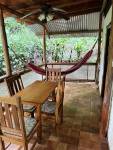 a porch with a hammock and a table and chairs at Hotel Entre Dos Aguas in Sámara