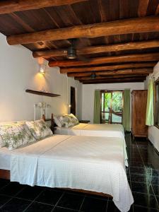 a bedroom with a large white bed with wooden ceilings at Hotel Entre Dos Aguas in Sámara