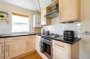 a kitchen with wooden cabinets and black counter tops at Lovely 3-bed 20 minutes to Central London in London