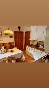 a kitchen with a table and white cabinets and a tableablish at Ferienwohnung mit WINTERGARTEN in Bahnhofsnähe in Eystrup +10 photos
