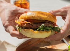 a person holding a hamburger in their hands at Novotel Paris Créteil Le Lac in Créteil
