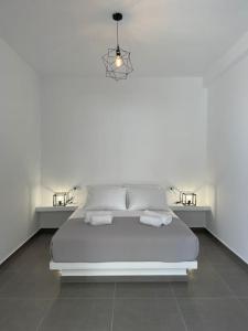 a white bedroom with a bed with two towels on it at Sklavadi Vineyard House in Kamari