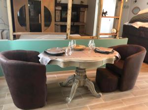 einen Tisch mit 2 Stühlen und einen Tisch mit Weingläsern in der Unterkunft Le Petit Paradis de Marcelise in Le Ponchel