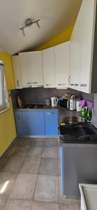 a kitchen with white cabinets and a blue sink at Apartman Luce in Krk