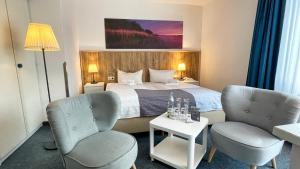 um quarto de hotel com uma cama e duas cadeiras em Hotel & Restaurant Seebrücke em Zingst