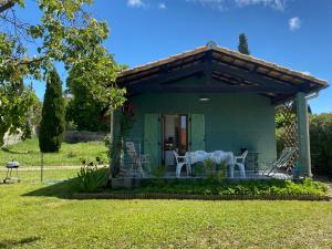 a green house with a table and chairs on the porch at Les gîtes de Pailhès in Pailhès